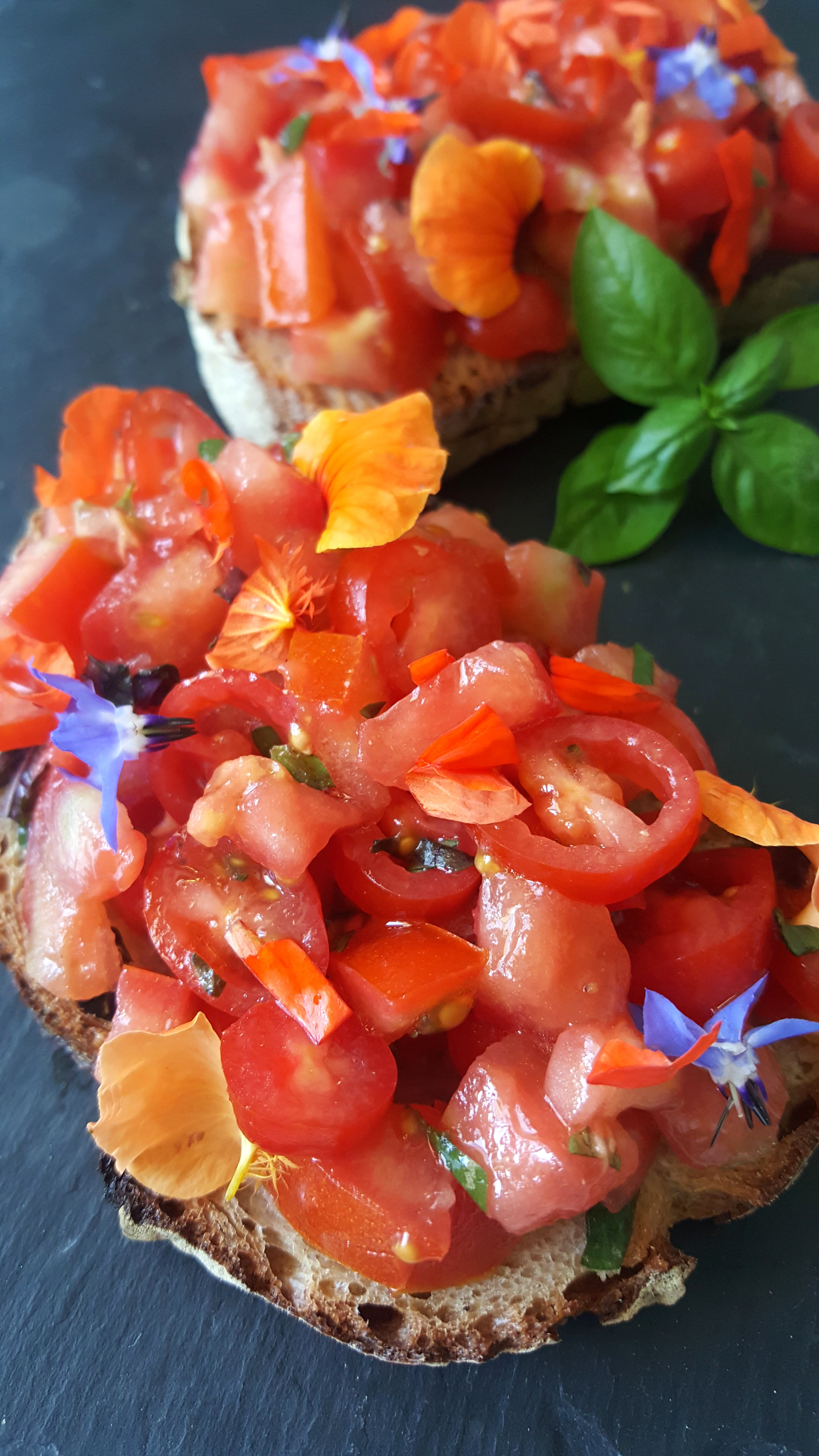 Tartines aux tomates rouges, basilic et fleurs comestibles