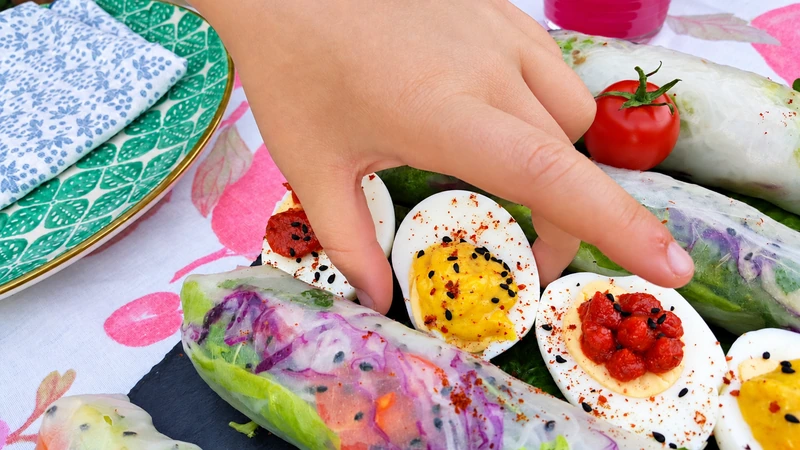 Rouleaux frais colorés et œufs garnis dans une composition estivale