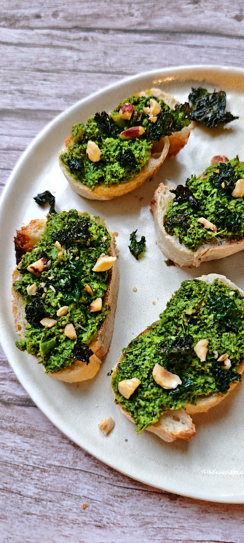 Tartines au pesto vert, noix et chips végétales sur une assiette claire