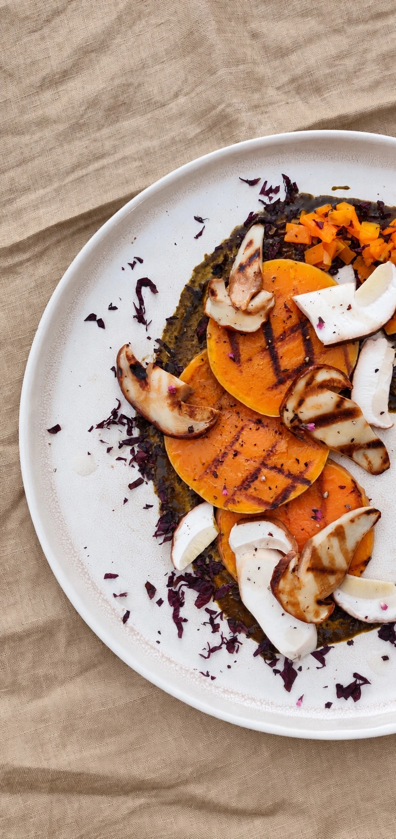 Patate douce grillée, champignons et chou rouge dressés sur une assiette claire