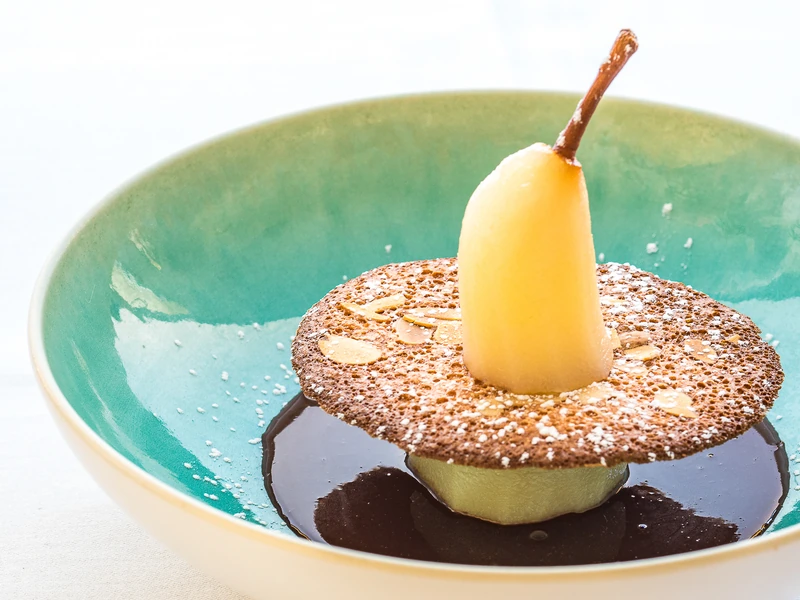 Dessert à la poire dressé dans une assiette turquoise