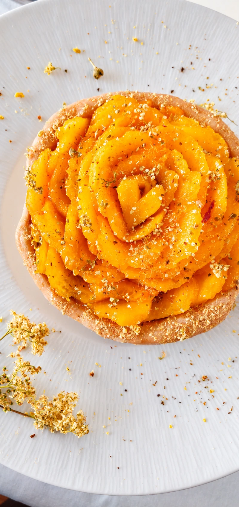 Dessert orange en spirale parsemé de fleurs séchées