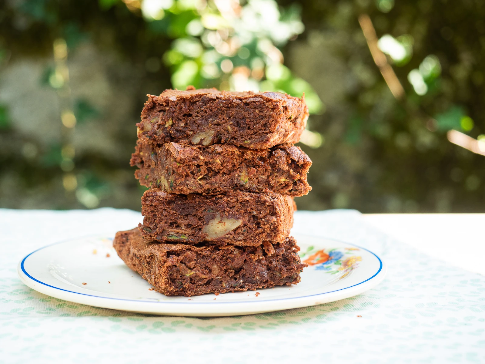 Brownies au chocolat empilés sur une assiette blanche, photographiés dans un jardin